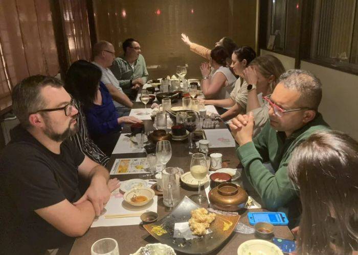 A sake tasting and izakaya tour in Beppu; guests are chatting together at a table covered in food and drinks.